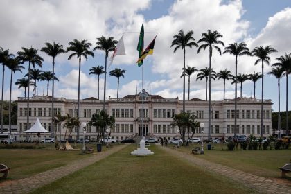 Edifício público brasileiro cercado por palmeiras sob um céu nublado.