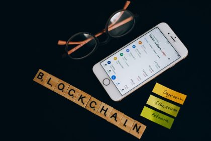 Smartphone exibindo dados do mercado de criptomoedas ao lado de elementos visuais associados à tecnologia blockchain.
